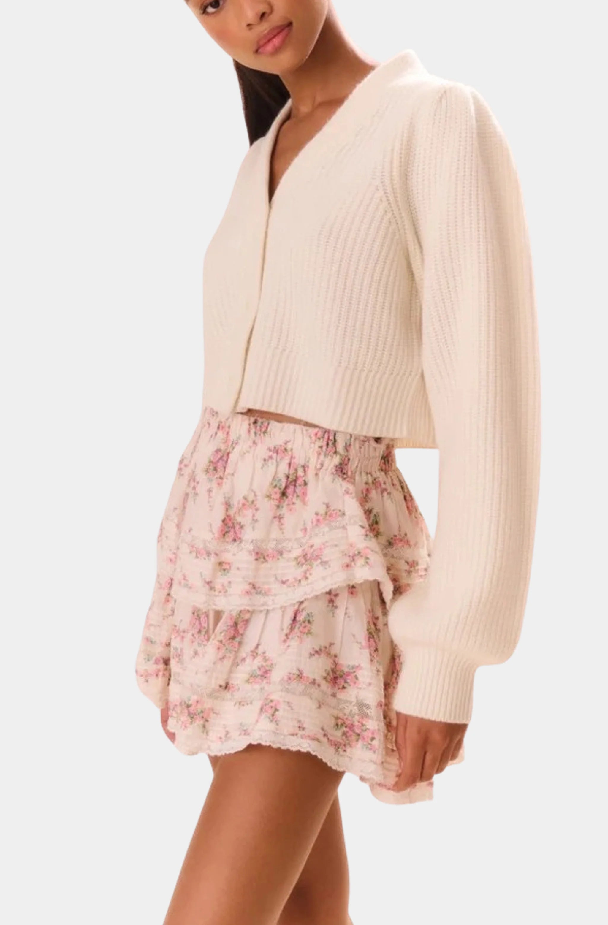 Side view of floral ruffle mini skirt paired with cream sweater.